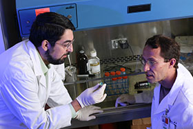 Photo of two scientists talking in the lab. Link to Closely Held Business Stock.