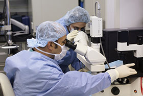 Photo of two scientists at the microscope. Link to Gifts of Life Insurance.